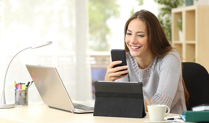 mulher respondendo mensagens no celular sorrindo