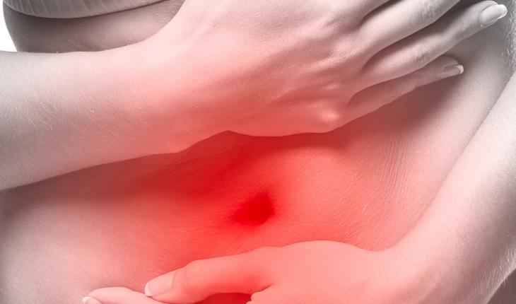 A imagem mostra a barriga de uma mulher em vermelho, ilustrando que ela está com dor na região abdominal. A meditação pode ser eficiente contra problemas gastrointestinais