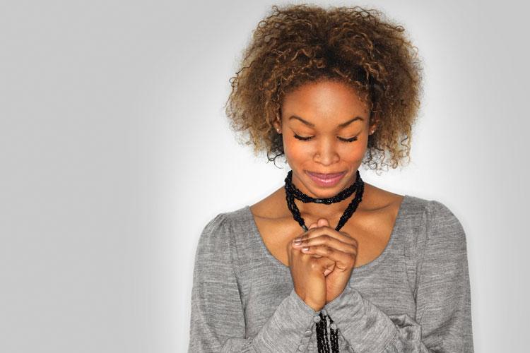 mulher negra fazendo oração de olhos fechados