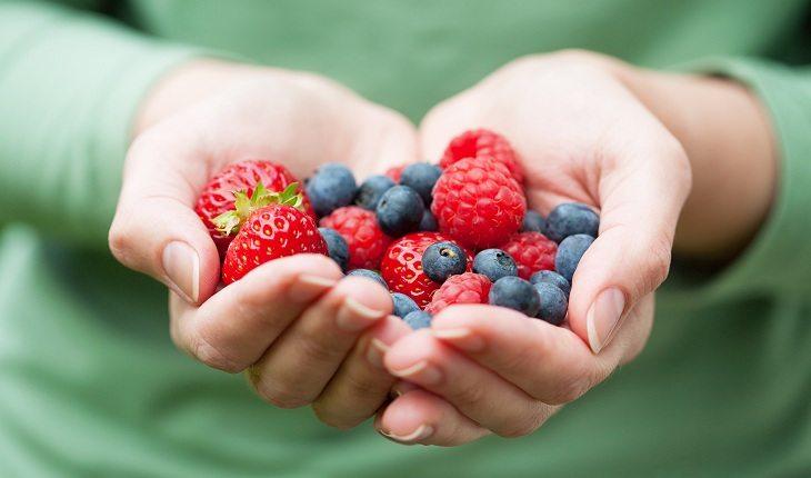 mão de mulher segurando frutas vermelhas