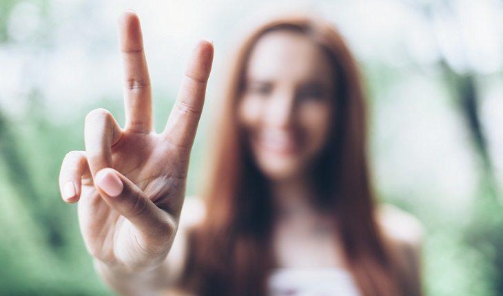 mulher fazendo sinal de paz com os dedos