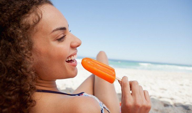 mulher tomando picolé na praia