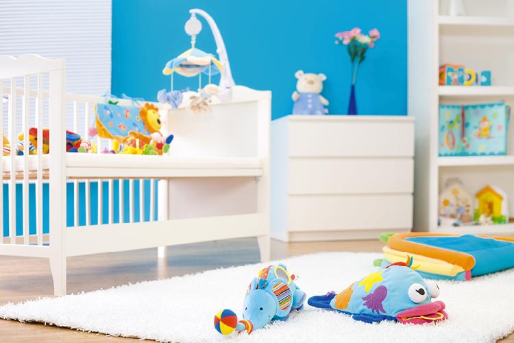 quarto de bebê azul com móveis brancos e brinquedos no chão