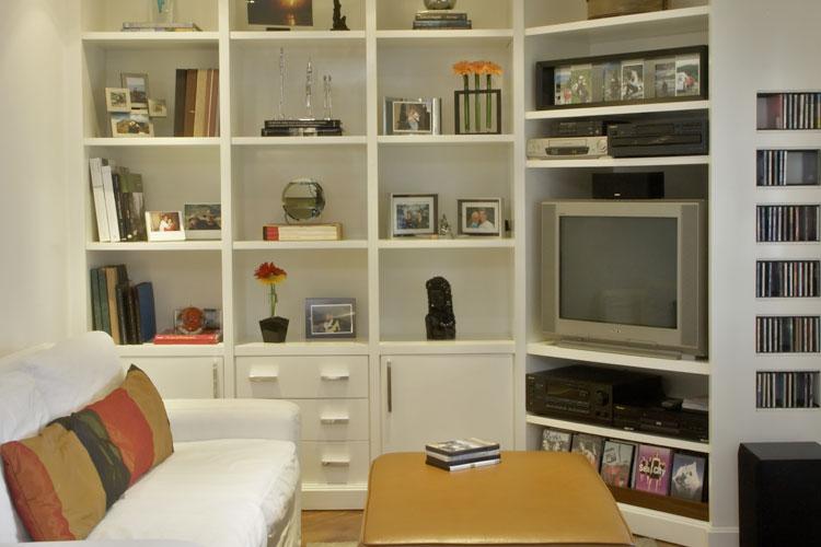 Sala com espaço pequeno mobiliada com estante, sofá e prateleiras