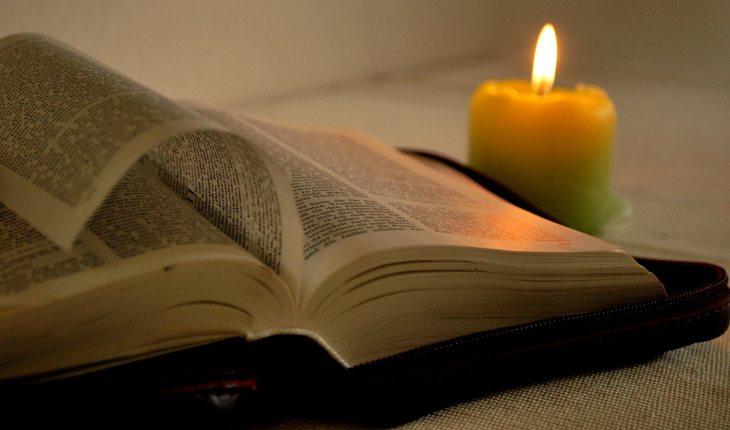 bíblica aberta com uma vela acesa ao lado