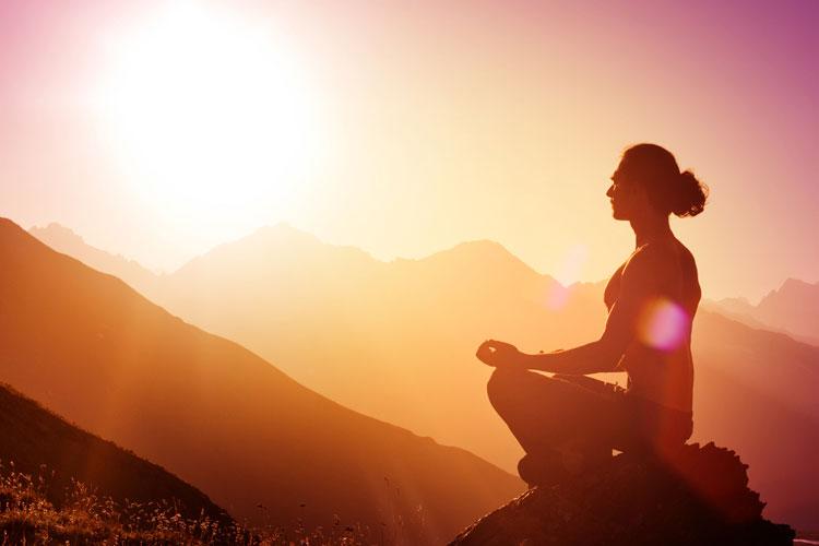 mulher meditando, recebendo as energias do sol