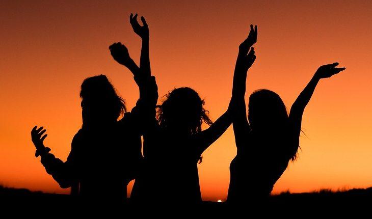 3 mulheres dançando com o pôr do sol atrás
