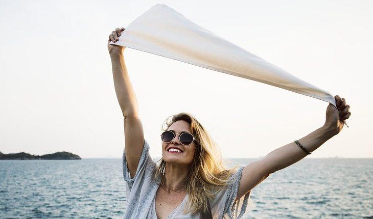 mulher segurando bandeira branca de frente com o mar