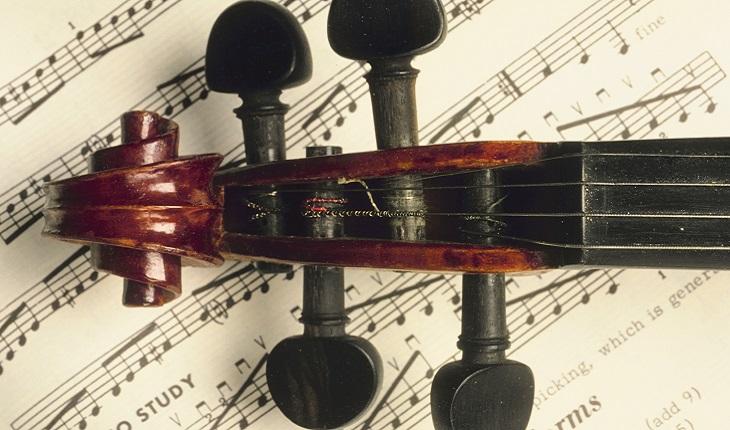 na foto há um violino em cima de uma partitura. Aprender a tocar instrumentos musicais ajuda você a ser uma mulher multitarefas