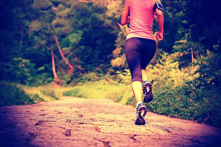 mulher correndo com roupa de ginástica em um caminho com árvores, exercícios para cada doença