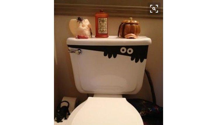 Na foto há uma ideia de decoração de Halloween com um vaso sanitário com desenhos de monstrinhos
