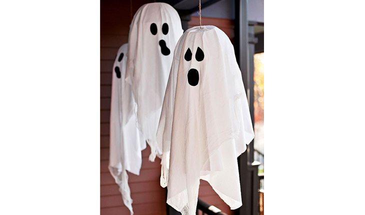 Na foto há uma ideia de decoração de Halloween com fantasmas feitos com balão e tecido branco.