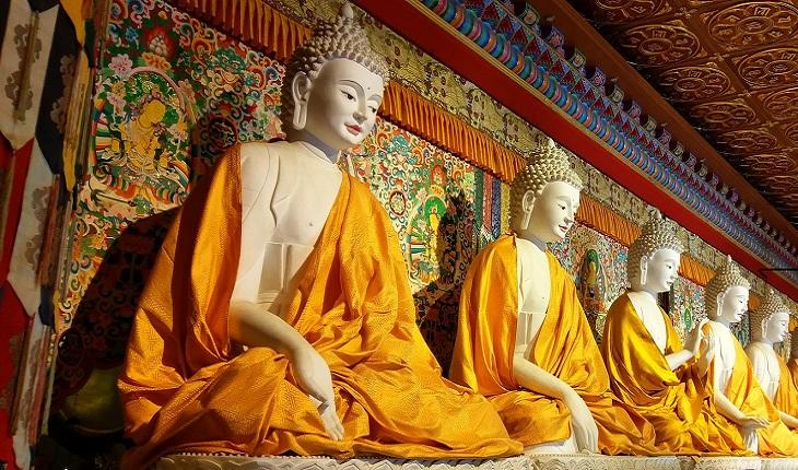 A foto mostra cinco estátuas de monges, uma representação de um tipo dos anjos budistas