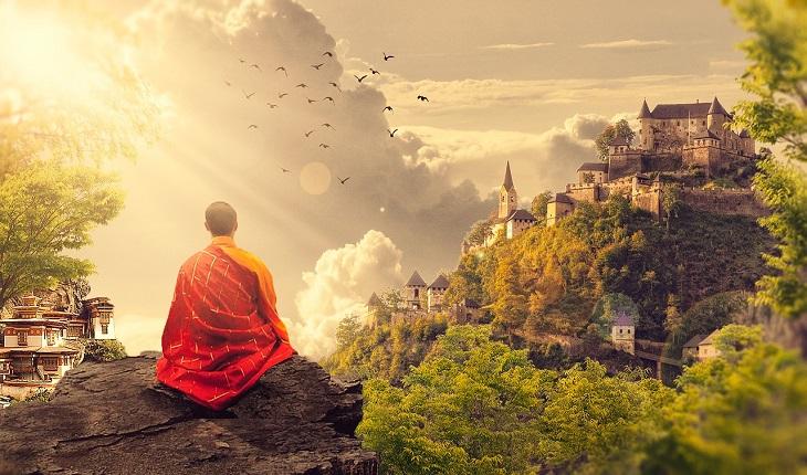 A foto mostra um monge meditando em uma montanha, uma representação de um tipo dos anjos budistas