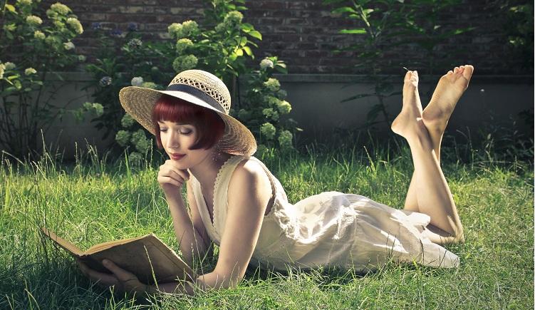 Mulher lendo livro deitada na grama
