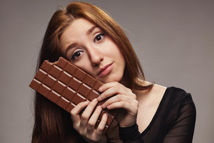 mulher triste segurando uma barra de chocolate