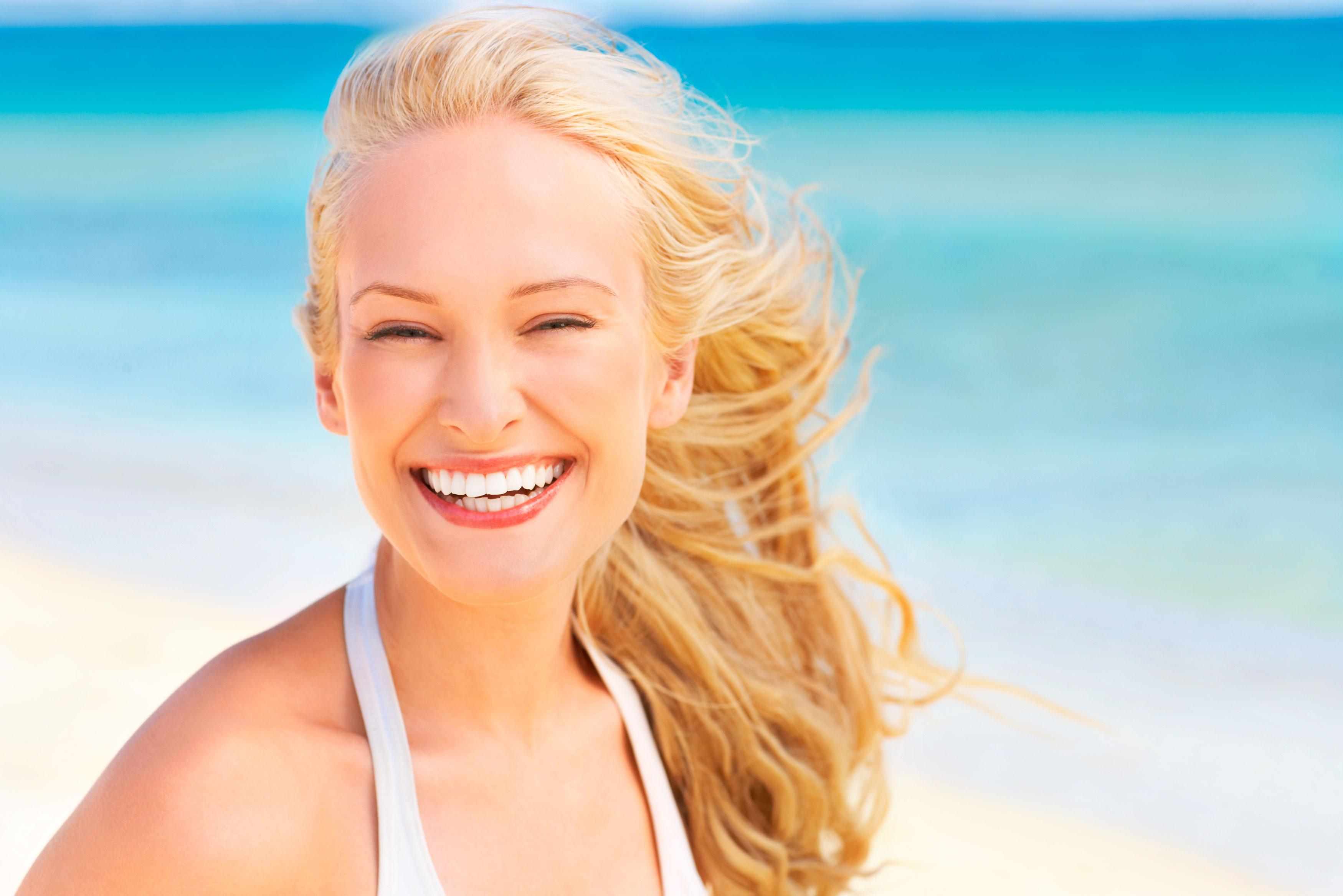 Mulher sorrindo com o lindo cabelo loiro no verão