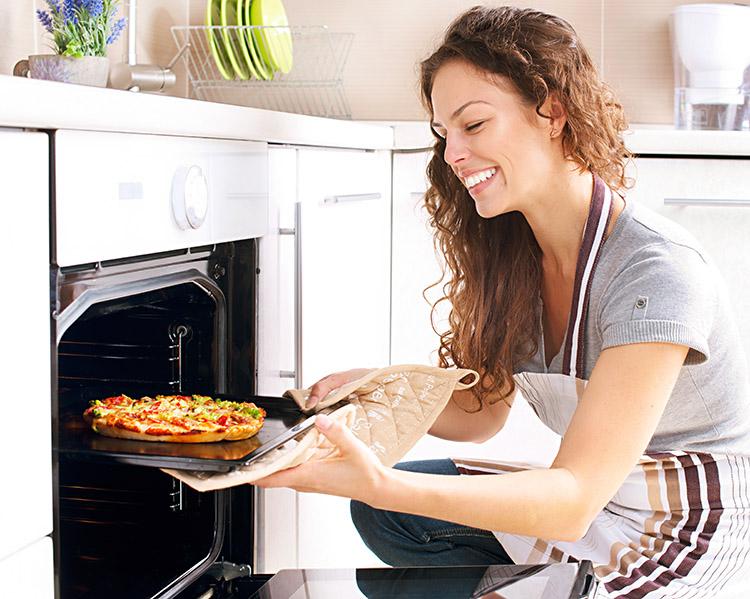 Mulher colocando pizza no forno