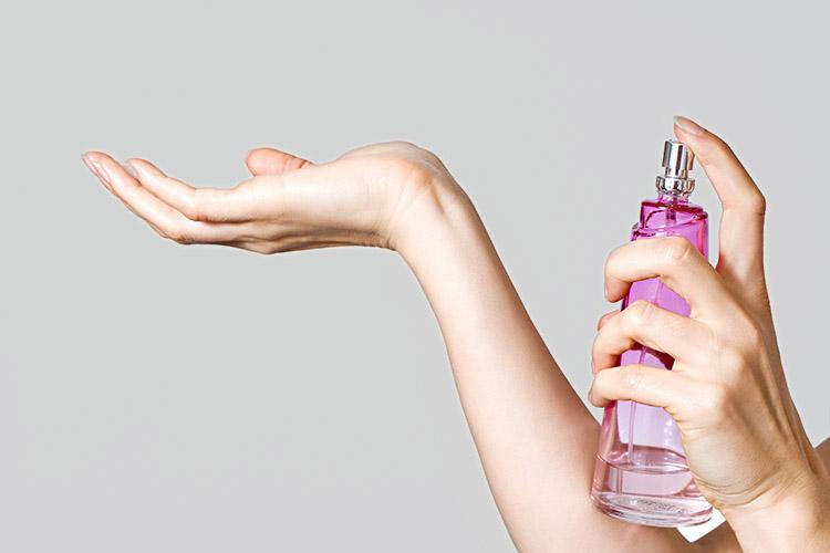 mulher aplicando perfume no pulso