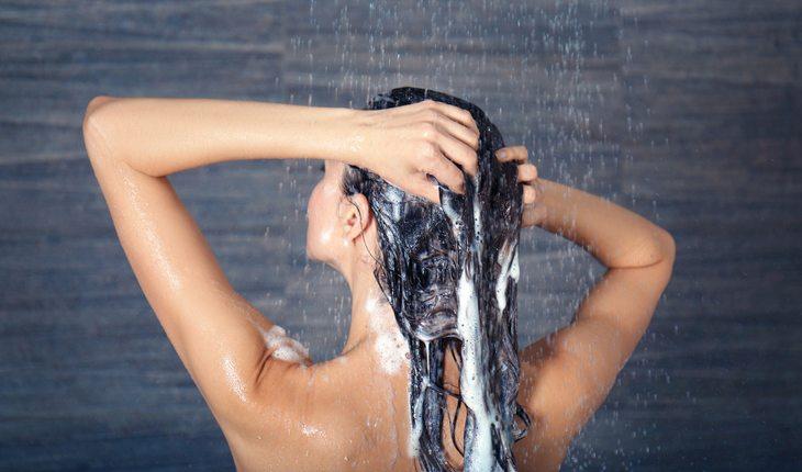 Cabelo longo. Na foto, mulher lavando os cabelos debaixo do chuveiro