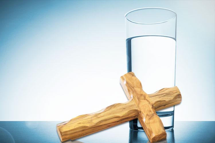 Copo com água benta e um crucifixo na frente