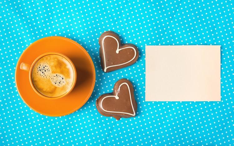 xícara de café perto de chocolates em forma de coração