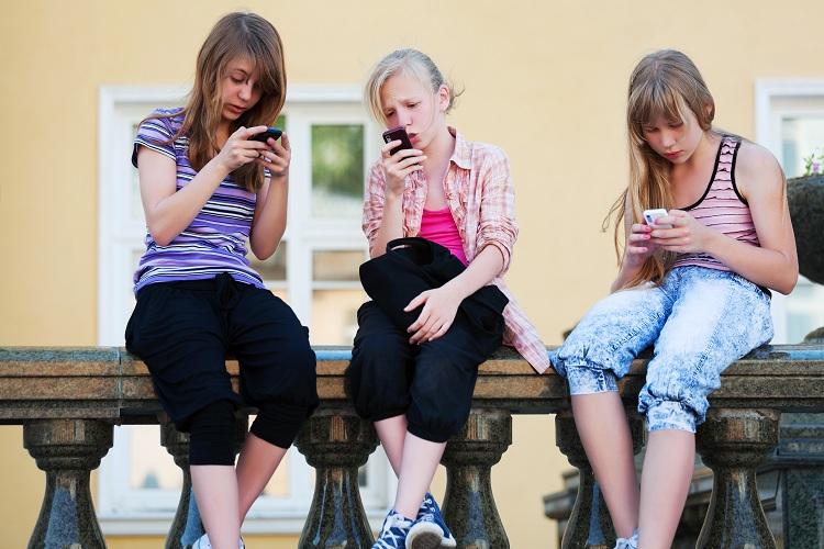 meninas-sentadas-digitando-celular-smartphone-aplicativo-snapchat-perfis-para-seguir