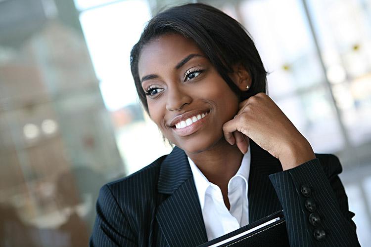 mulher negra com terninho, sorrindo e feliz depois de entrevista de trabalho concursos públicos