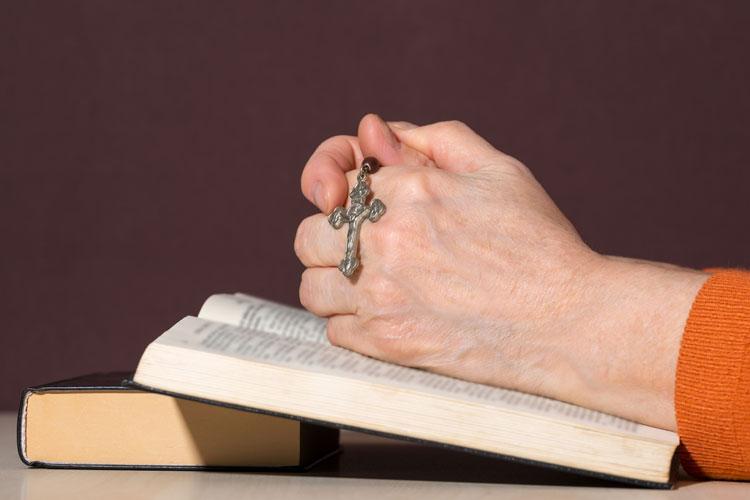 Oráculo da fé: mãos sobre uma Bíblia segurando um terço