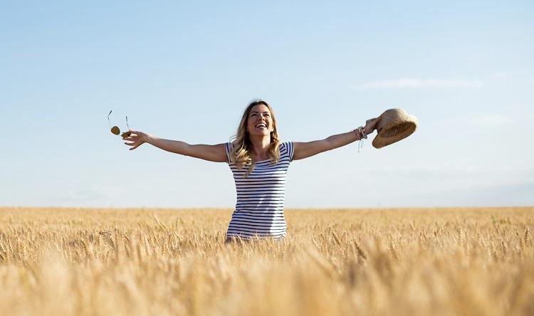 autoconhecimento: mulher feliz num campo tomando sol