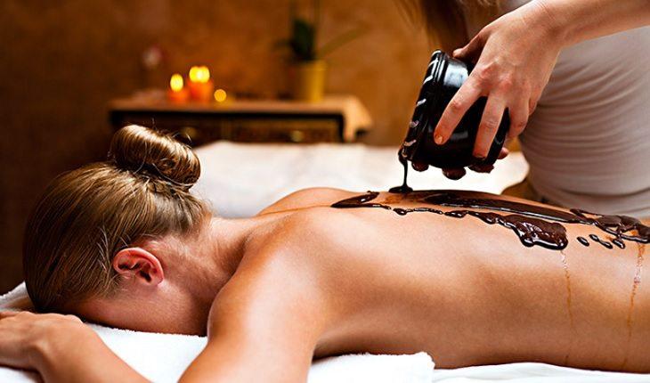A foto mostra uma mulher recebendo massagem na chocolaterapia