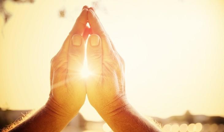 pessoa com mãos ao alto rezando
