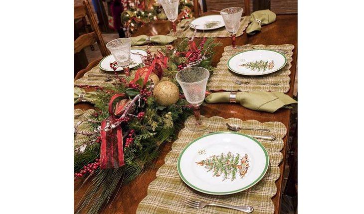 mesa decorada para o natal com sousplat verde-musgo, pratos brancos e enfeites verdes com fitas vermelhas