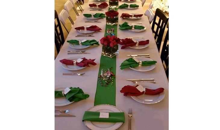 mesa comprida com diversos pratos e decoração de natal nas cores verde e vermelha