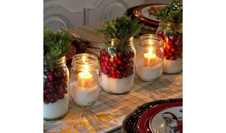 mesa de natal com velas dentro de potes de vidro decorados em vermelho e verde