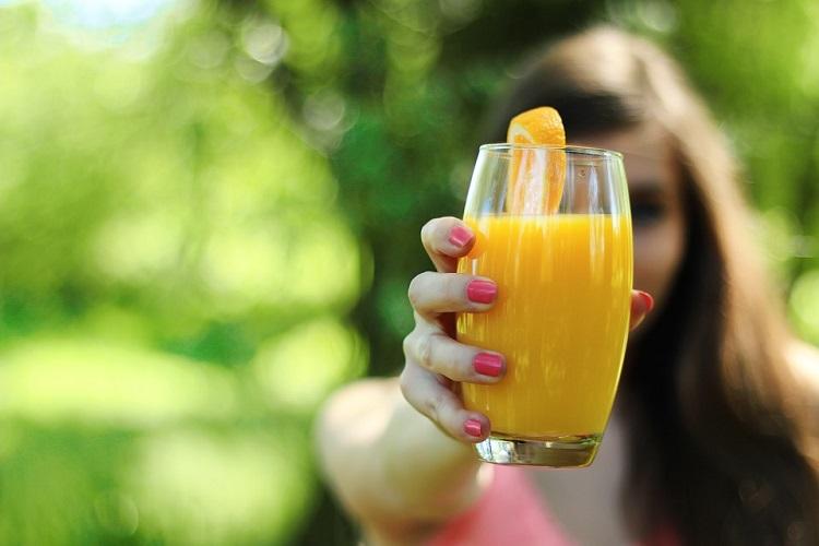 mulher segurando copo suco de laranja