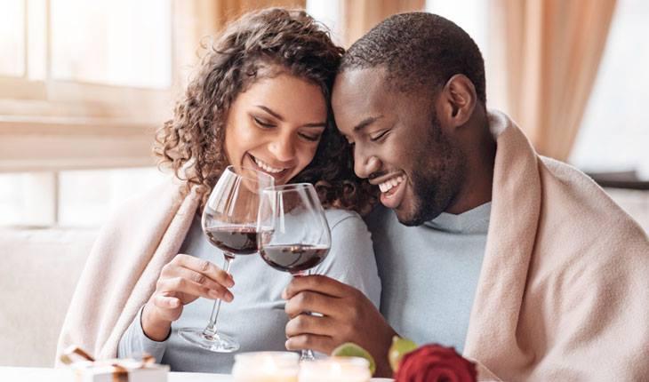 Casal tomando vinho abraçados em restaurante