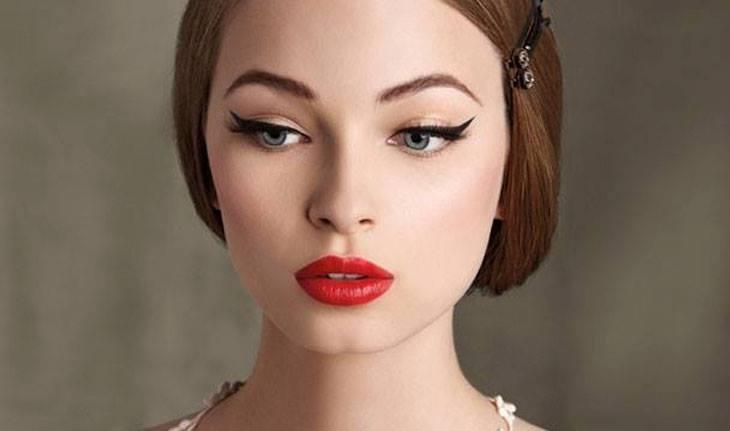 Mulher usando maquiagem vintage: olhos com delineado gatinho e batom vermelho