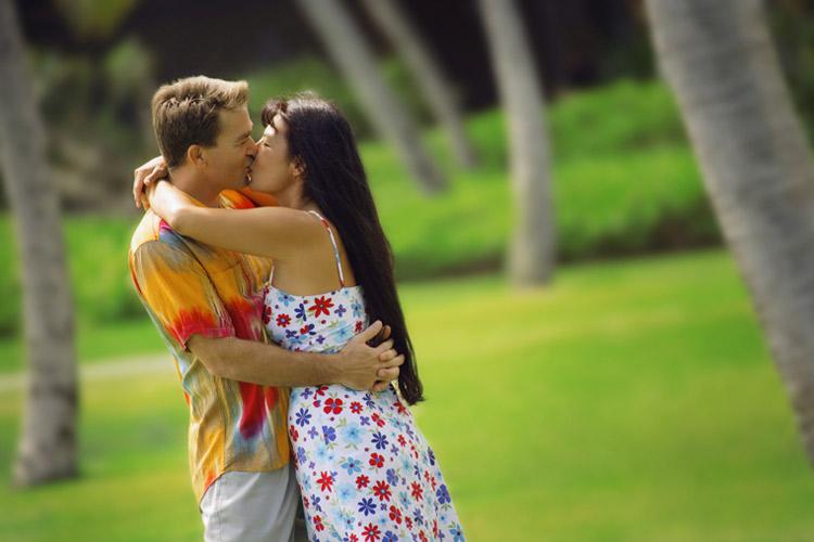 casal abraçado e se beijando em um campo com árvores