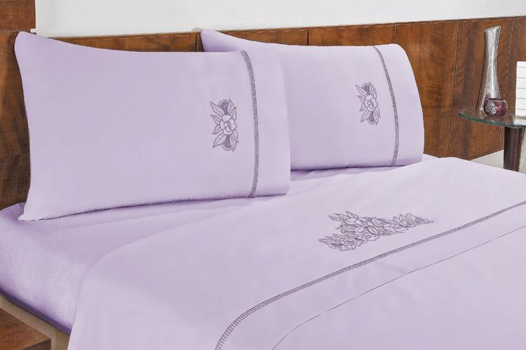 Mesa com lençol branco e almofadas coloridas, com criado mudo feito de uma cadeira antiga