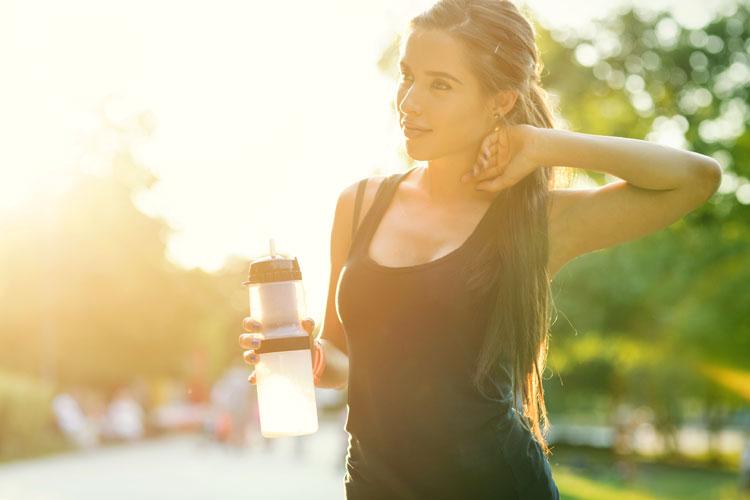 mulher de rabo, com garrafa de água na mão e roupa para praticar exercícios físicos