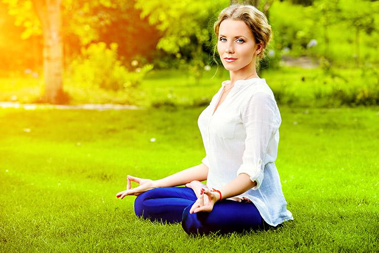 mulher meditar relaxar sentada grama pernas cruzadas