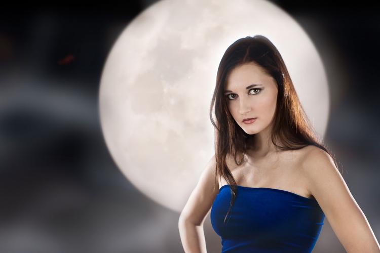 mulher, com cabelo escuro longo e blusa azul, e lua cheia