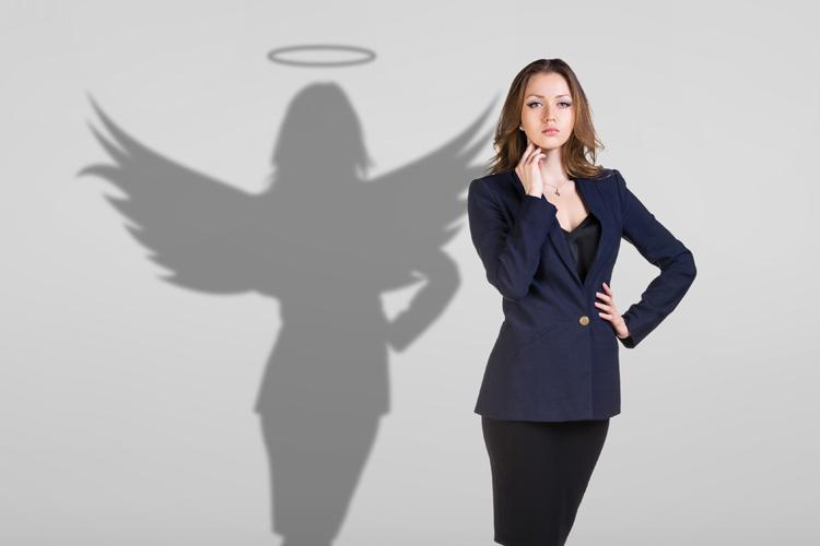 mulher parada em frente de uma parede com sombra em formato de anjo