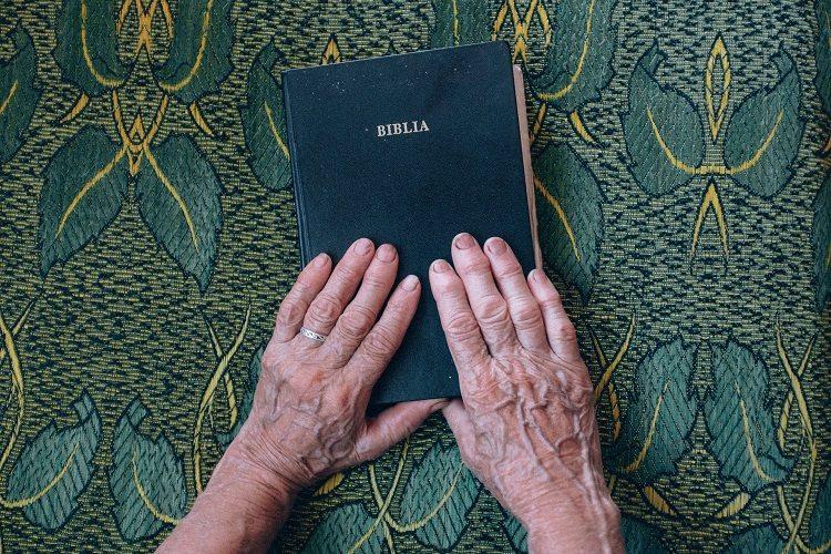 Mãos idosas sobre a bíblia em prece ao poder do salmo 40