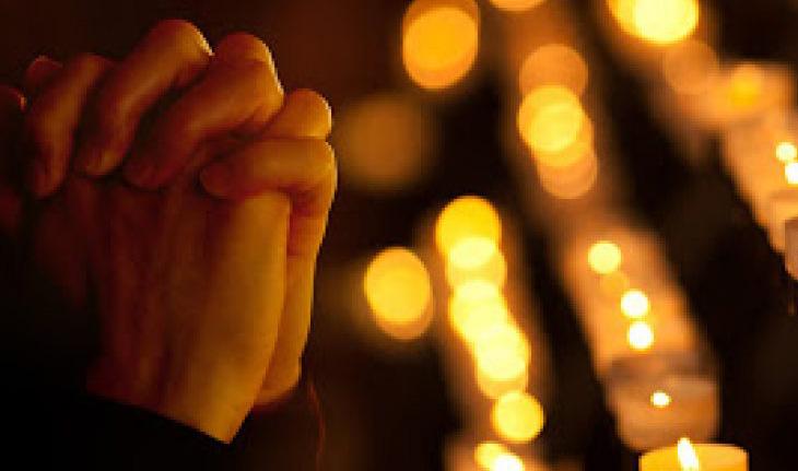 Mãos rezando com luzes ao fundo