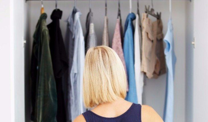 mulher olhando para roupas no armário