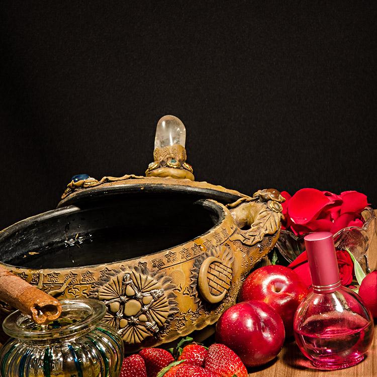 vasilha com óleo e uma tampa, maçãs, canela em pau, perfume, pétalas de rosas vermelhas e morangos
