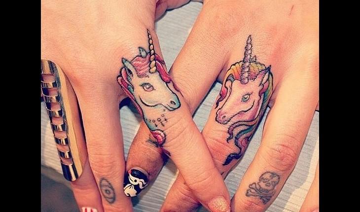 Tatuagem de um unicórnio nos dedos das mãos, colorido em rosa e azul