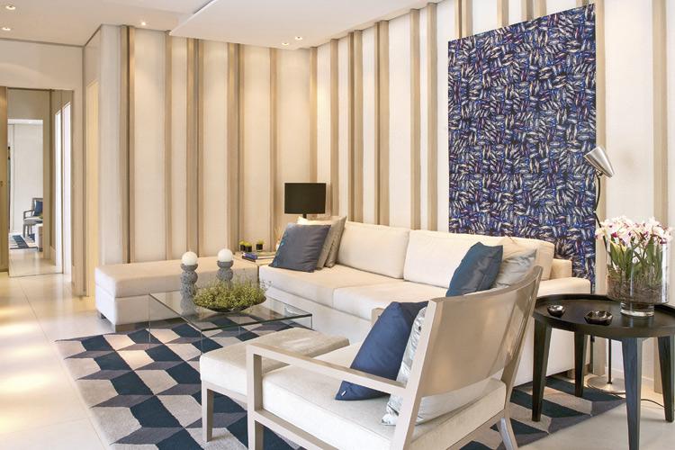 A parede da sala estampada com listras e o tapete com motivos geométricos combinados com cores neutras dão leveza e dinamismo ao ambiente.